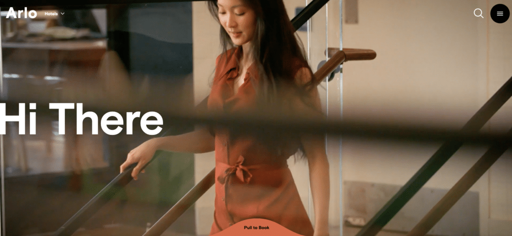 A screenshot of the arlo hotel website, a woman walks down the stairs